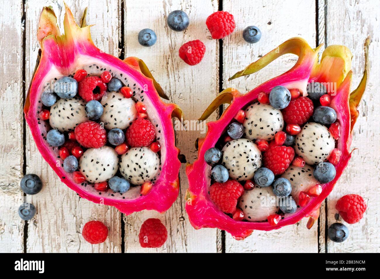 Colorful dragon fruit salads with raspberries and blueberries over a white wood background Stock Photo