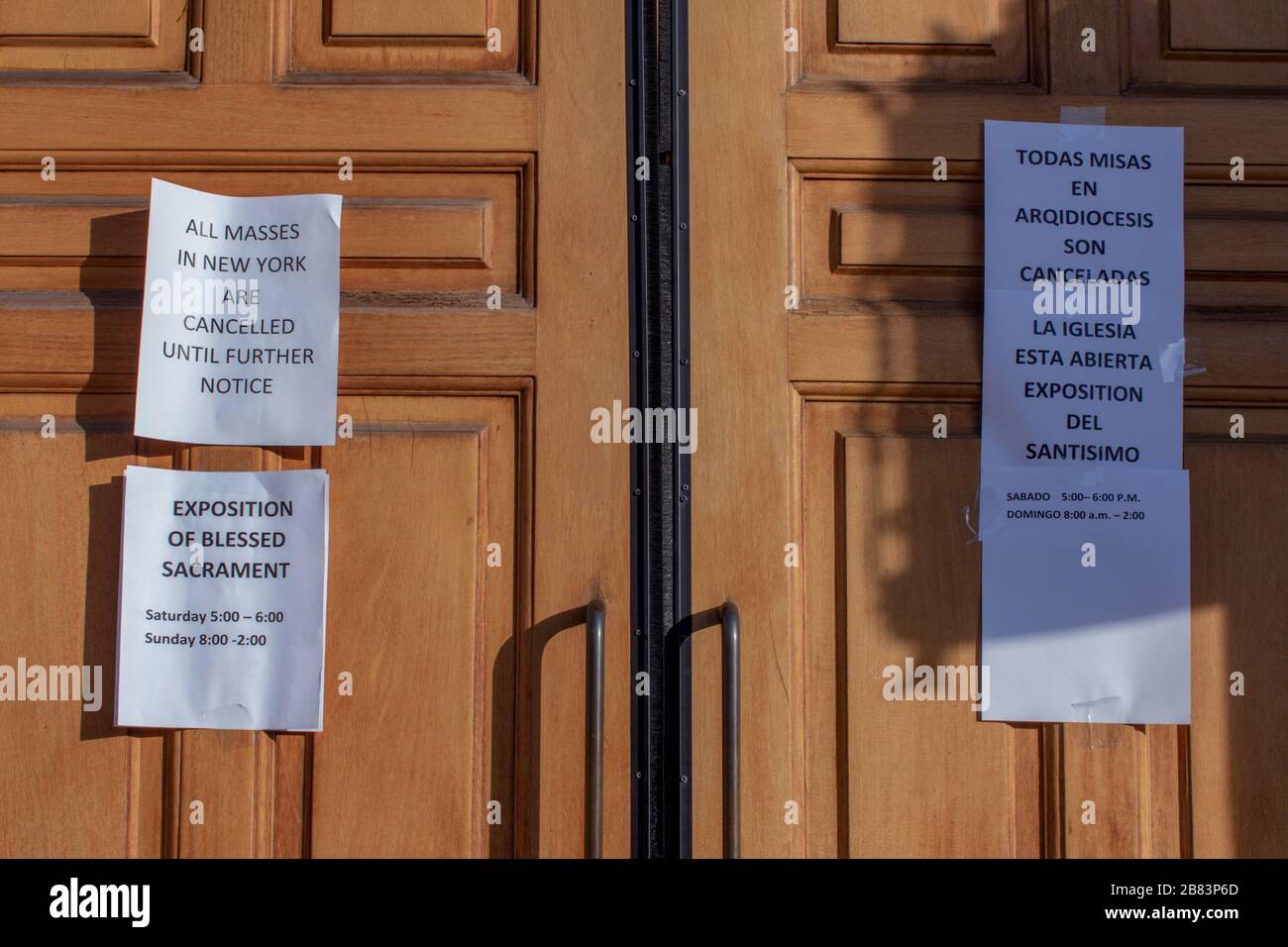 signs on the door of the Church of the Good Shepherd in English and Spanish stating masses are cancelled due to coronavirus or covid-19 pandemic Stock Photo