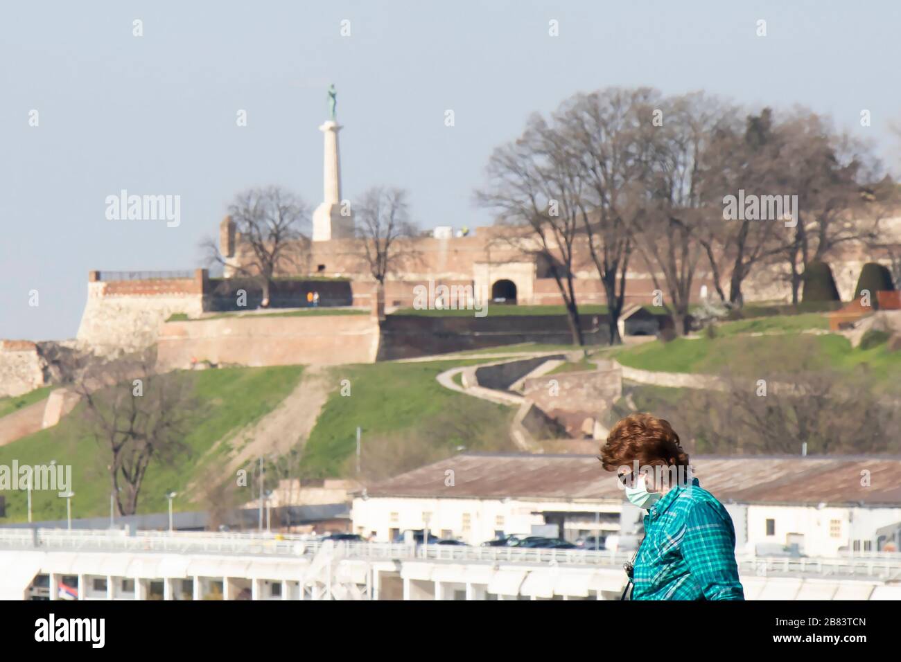 Belgrade, Serbia - March 18, 2020: Women wearing protective mask while walking with Kalemegdan fortress in the background, in the time of coronavirus Stock Photo
