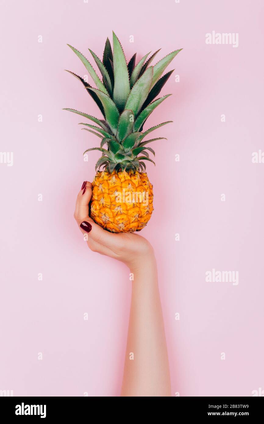 Hands with pineapple on stylish pink background. Stock Photo