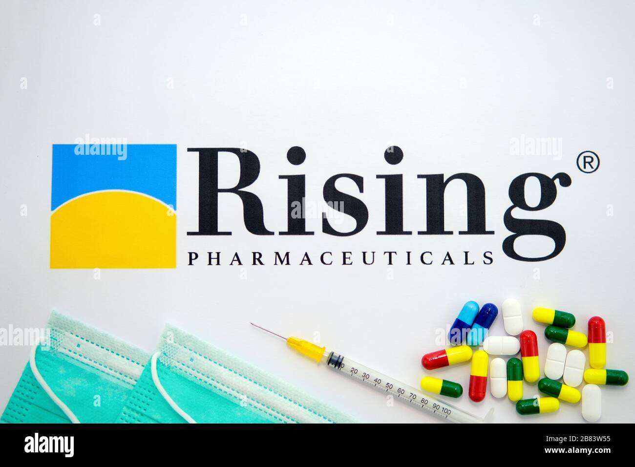 Rising Pharmaceuticals logo printed on paper and masks, syringe and pills on top of it. The company makes new Chloroquine drug against Covid-19. Stock Photo