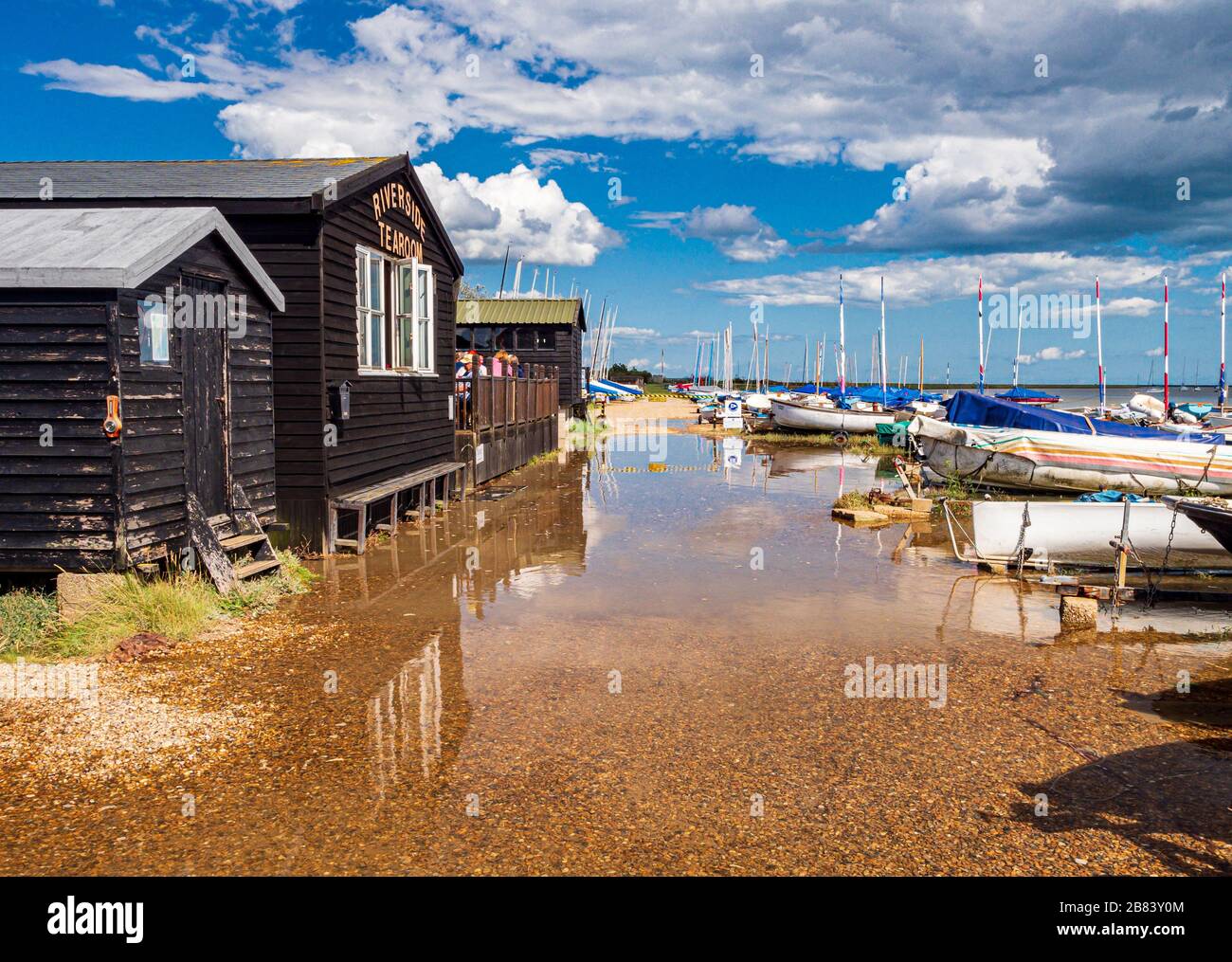 Views of Orford in Suffolk at High Tide with fishing huts and boats Stock Photo