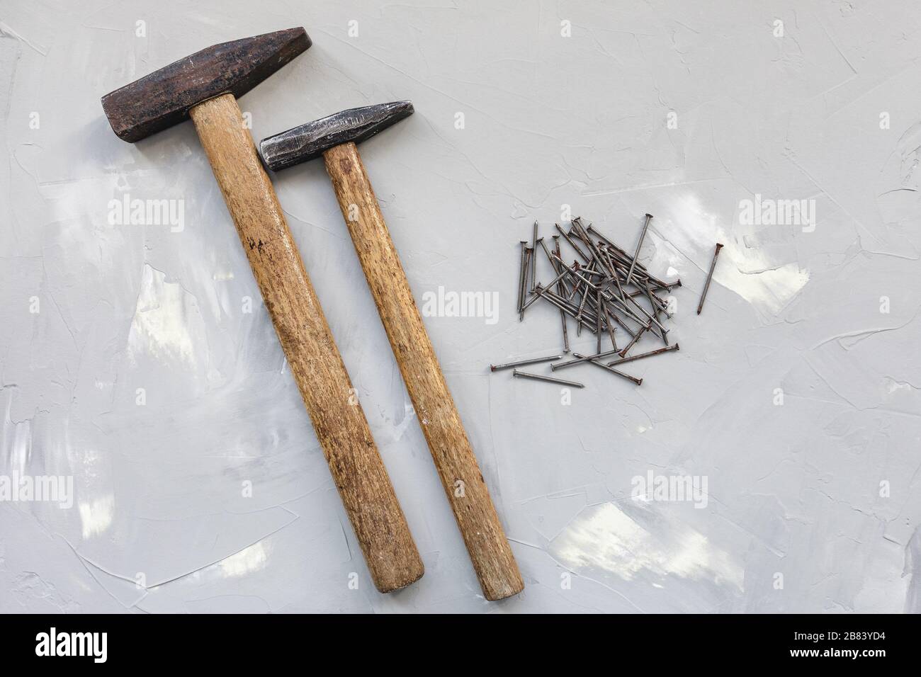 Two hammers and old rusty nails on gray background, carpentry concept, copy space Stock Photo