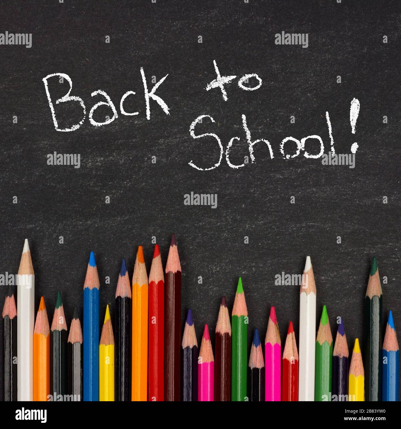 Bottom border of colorful pencil crayons against a blackboard with Back to School writing in chalk Stock Photo