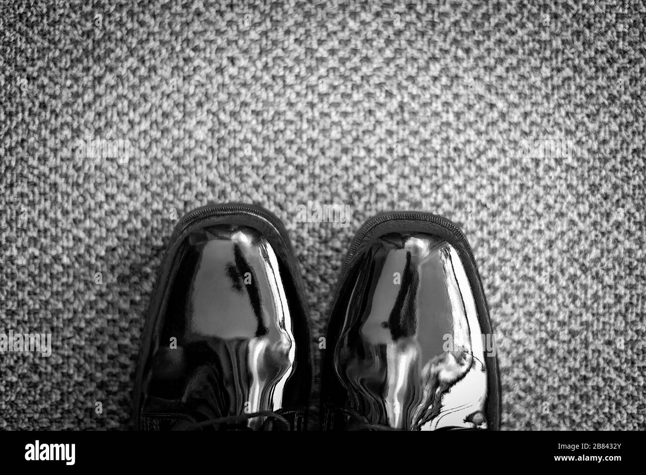Black and whte textured and patterned carpet with pantent leather shoes seen from above Stock Photo