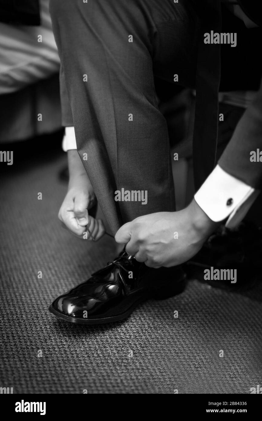 Patent leather shoes being tied by a Bridegroom before his wedding Stock Photo