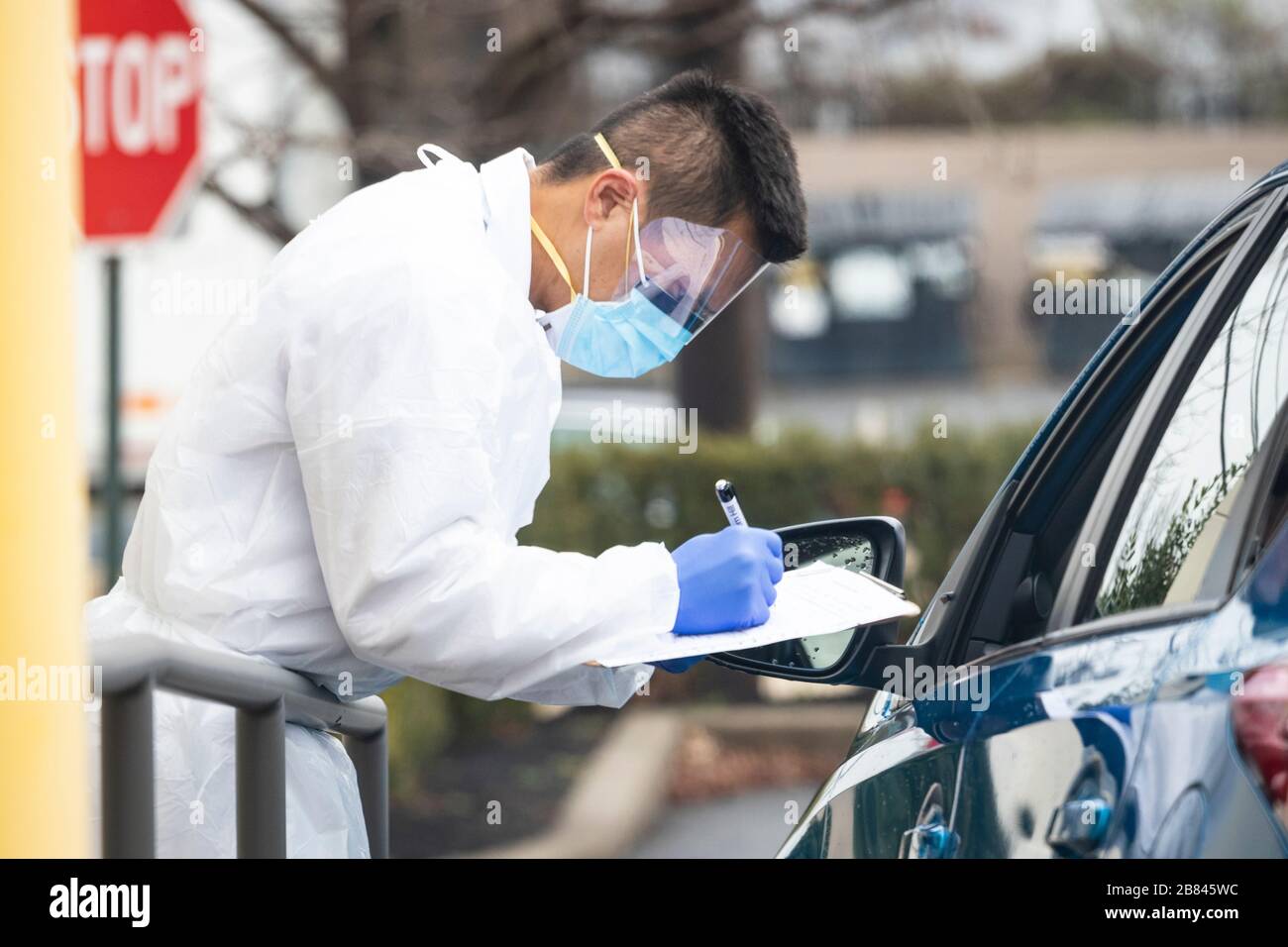 Healthcare worker administers COVID-19 test to patients in drive-thru clinic Stock Photo
