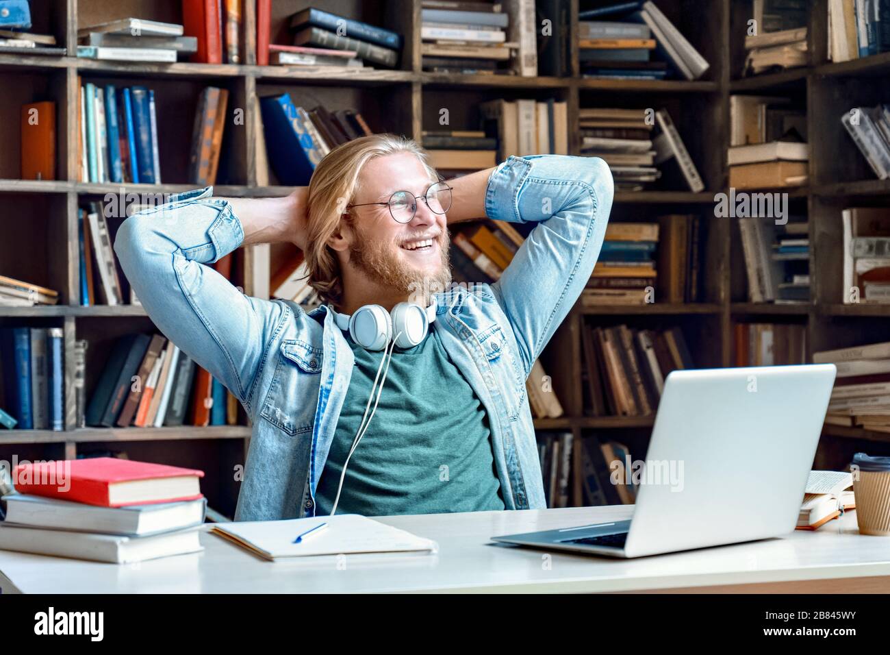 Happy relaxed man student resting finished study work sit in library