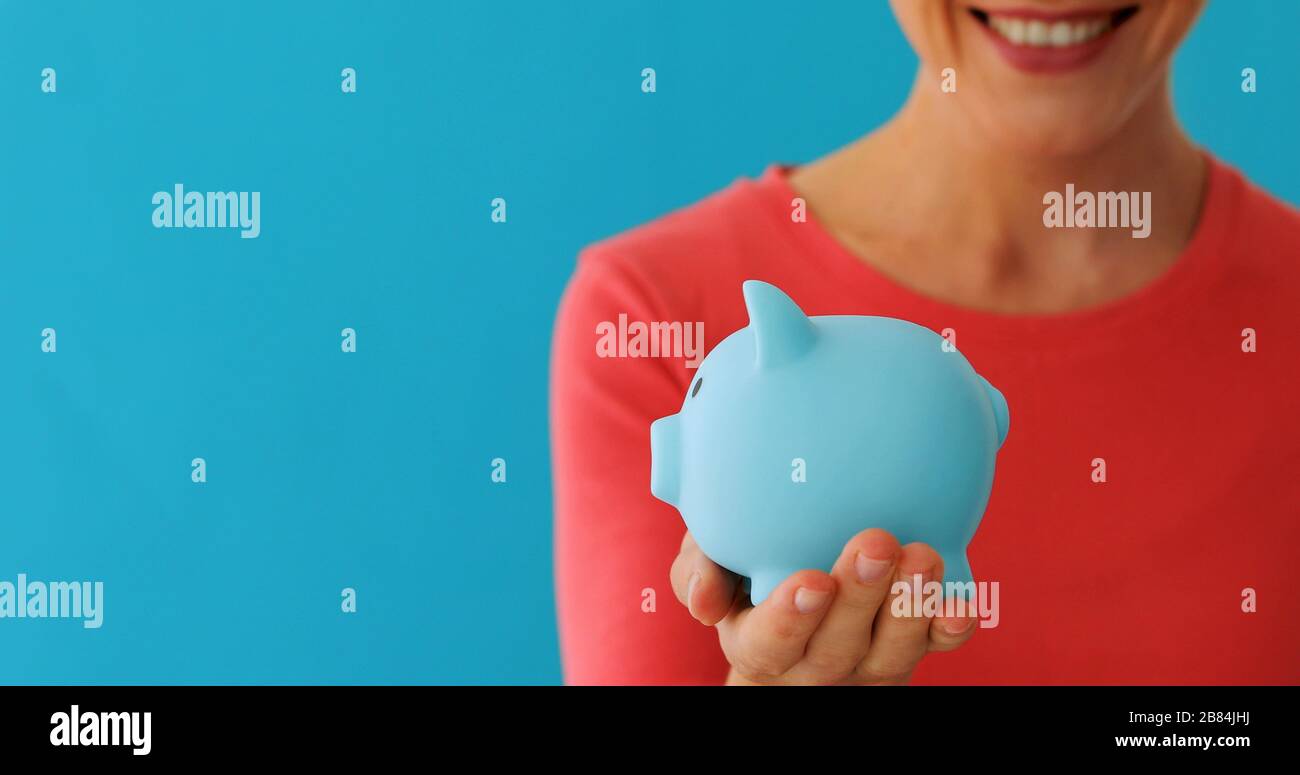 Smiling woman carrying piggy bank Stock Photo