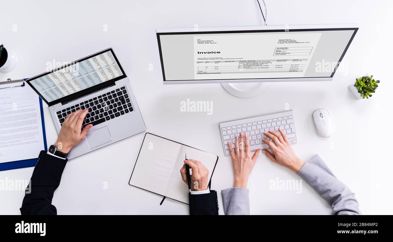 Close-up Of Two Businesspeople Analyzing Invoice On Computer Stock Photo