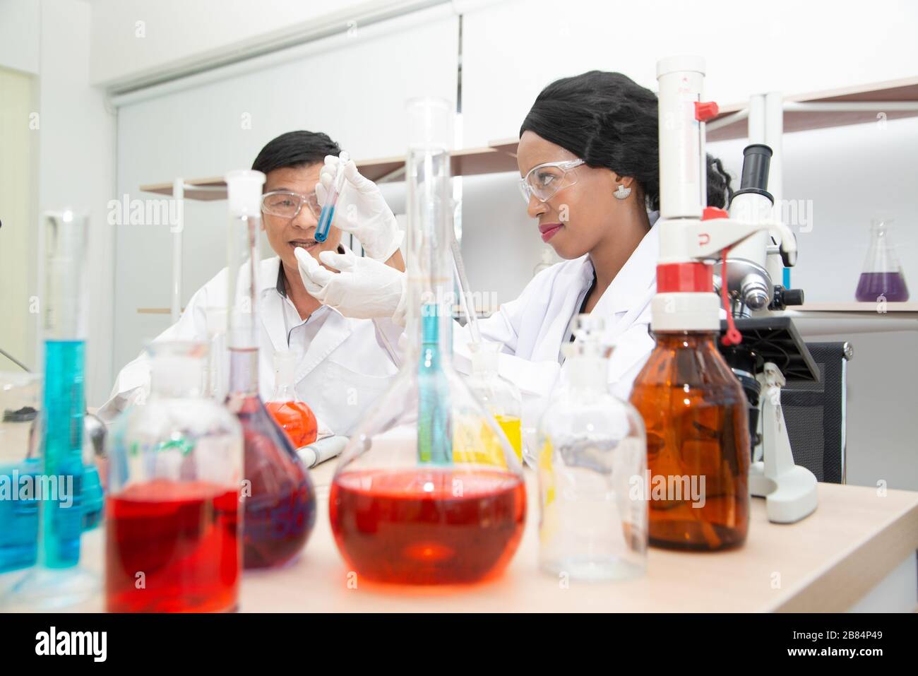 Two scientists are working in laboratory. Young female researcher and