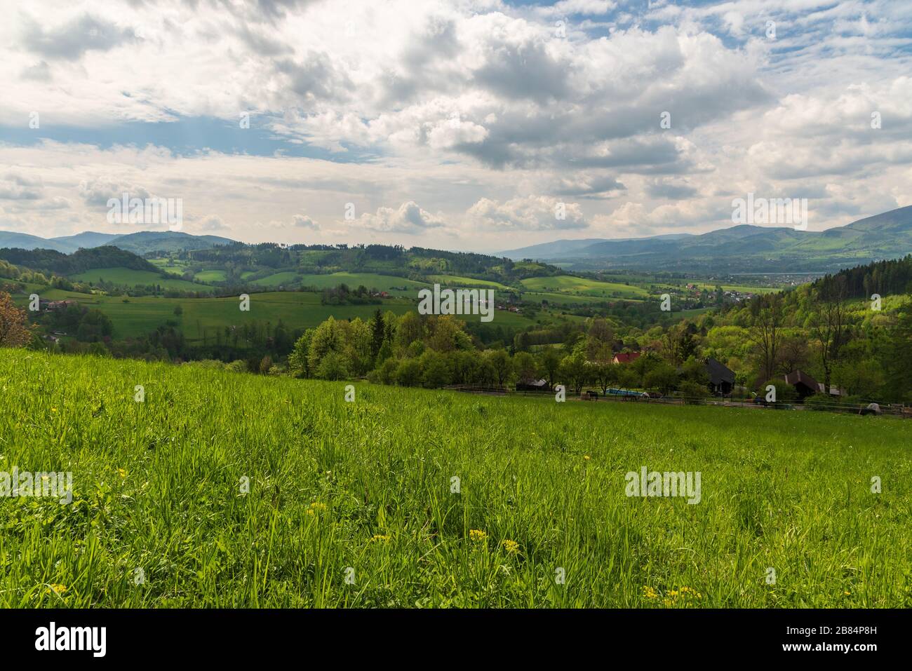 rolling landscape around Vendryne village in Czech republic with hills, meadows, trees, dispersed settlement and blue sky with clouds Stock Photo