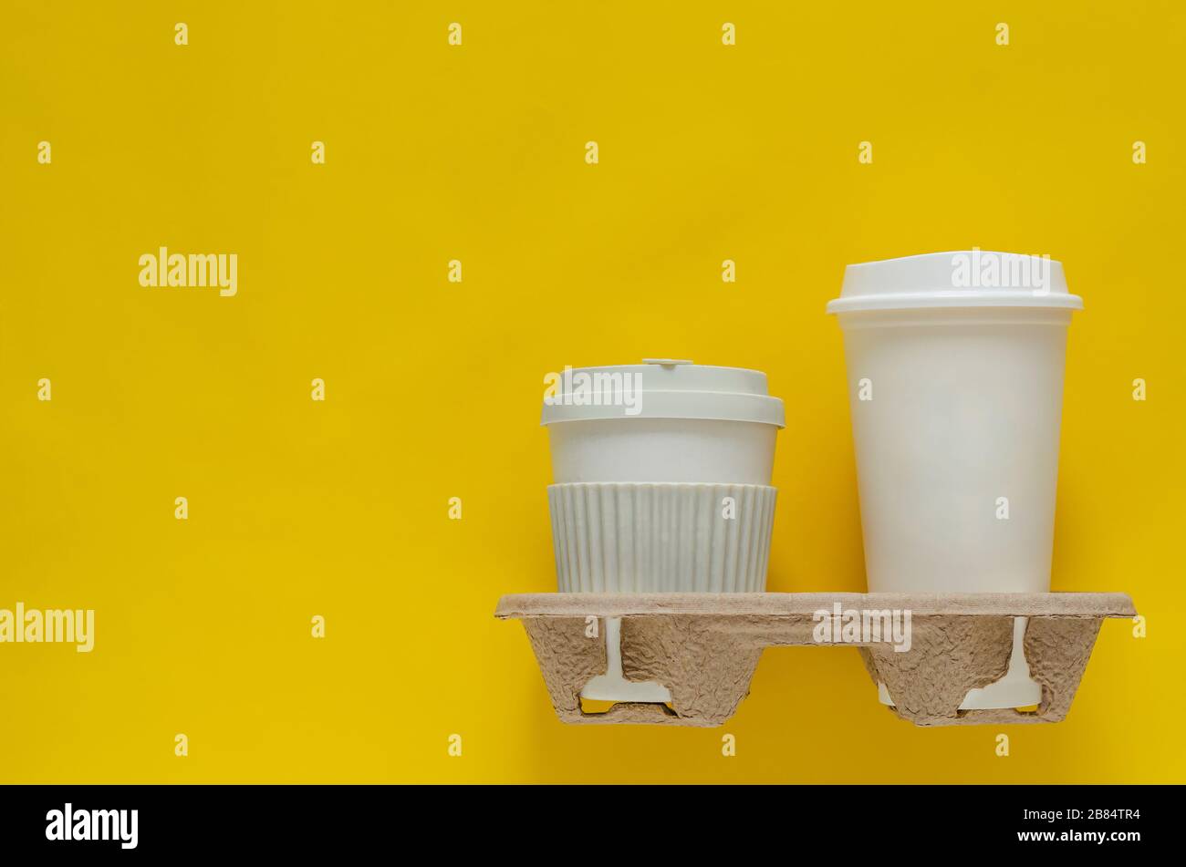 The recycle cups of coffee in reuse paper tray put on yellow paper background for World environment concept. Stock Photo