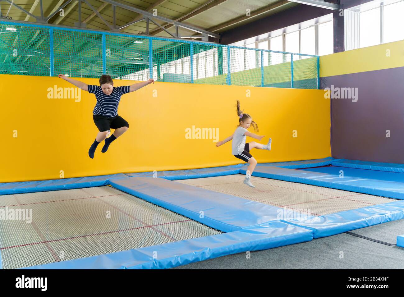 Happy smiling small kids jumping on indoors trampoline in entertainment ...