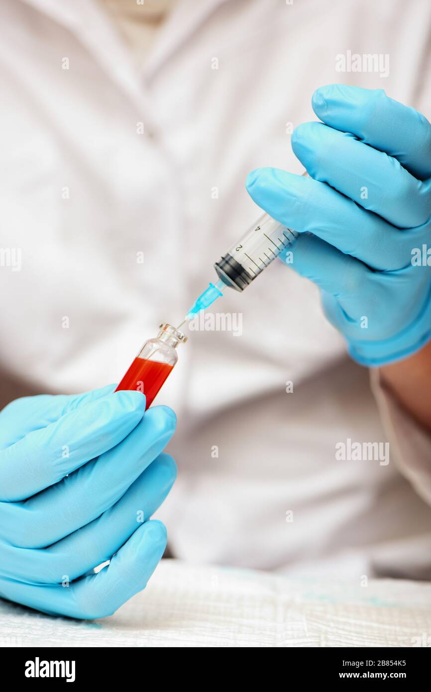 Doctor in medical gloves injecting vaccine into syringe. Concept Coronavirus nCov 2019. Vertical. Stock Photo