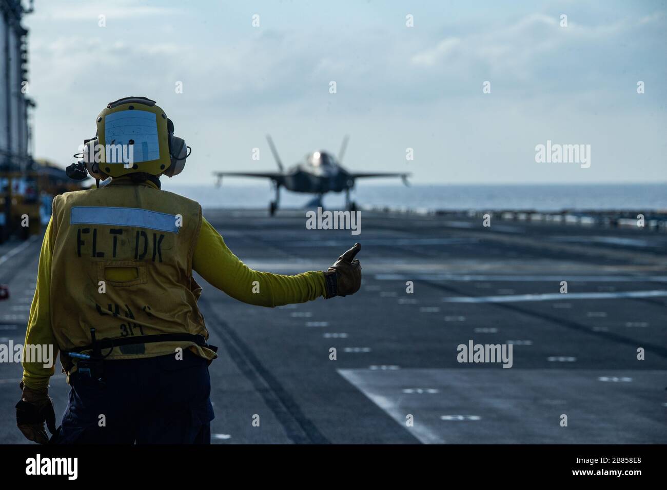 PHILIPPINE SEA (March 18, 2020) An F-35B Lightning II fighter aircraft with Marine Medium Tiltrotor Squadron 265 (Reinforced), 31st Marine Expeditionary Unit (MEU), is cleared for takeoff by a Sailor aboard amphibious assault ship USS America (LHA 6). America, flagship of the America Expeditionary Strike Group, 31st MEU team, is operating in the U.S. 7th Fleet area of operations to enhance interoperability with allies and partners and serve as a ready response force to defend peace and stability in the Indo-Pacific region. (Official U.S. Marine Corps photo by Cpl. Isaac Cantrell) Stock Photo