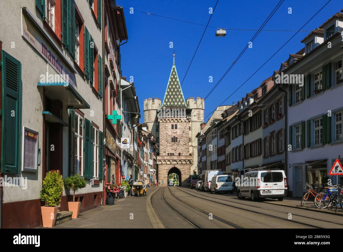Nice view of the street Spalenvorstadt in Basel, leading to the gate Spalentor. Its square main tower, flanked on each side by two round towers, is a... Stock Photo