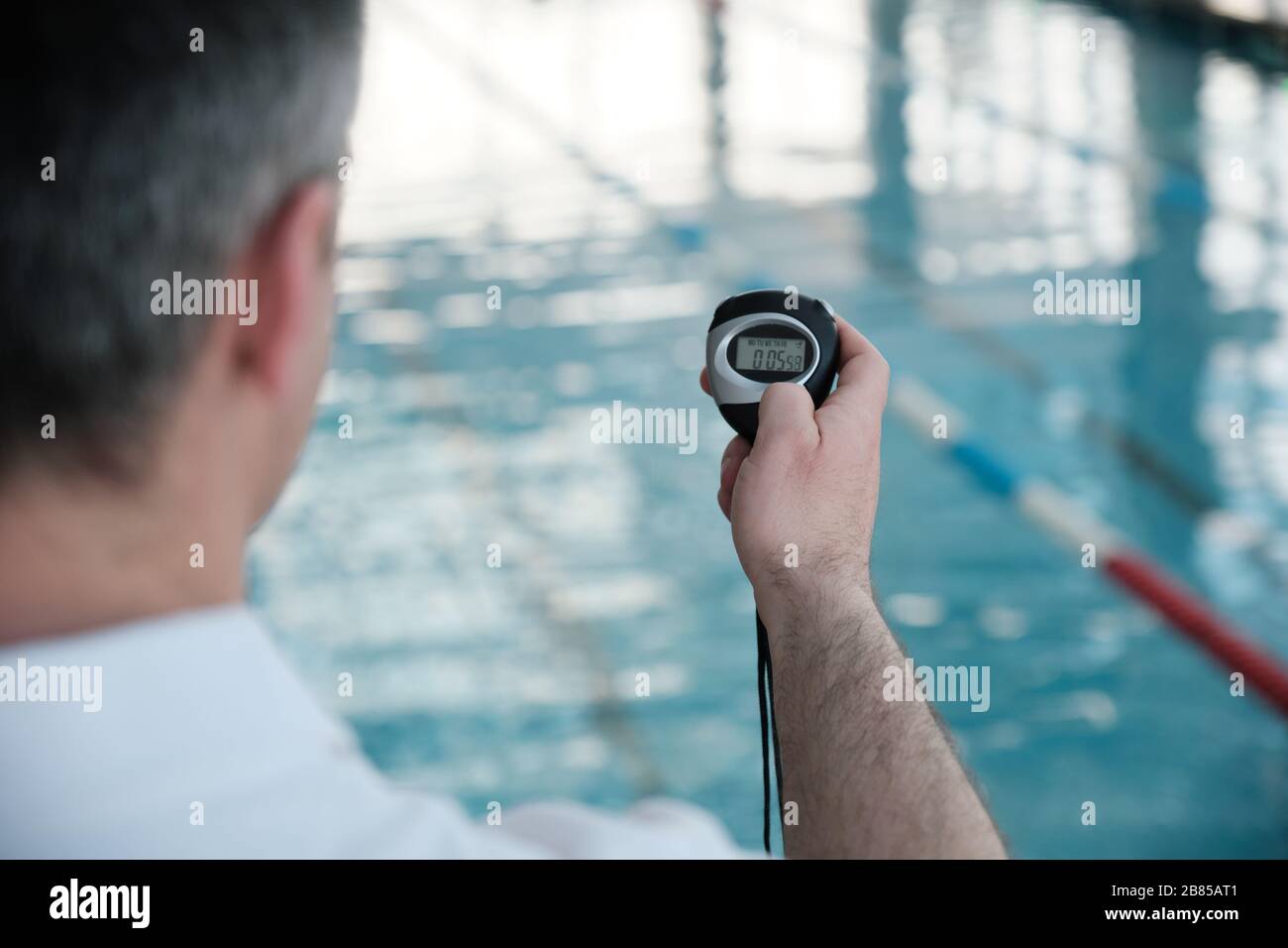 Over shoulder view of coach using stopwatch while checking time of swim