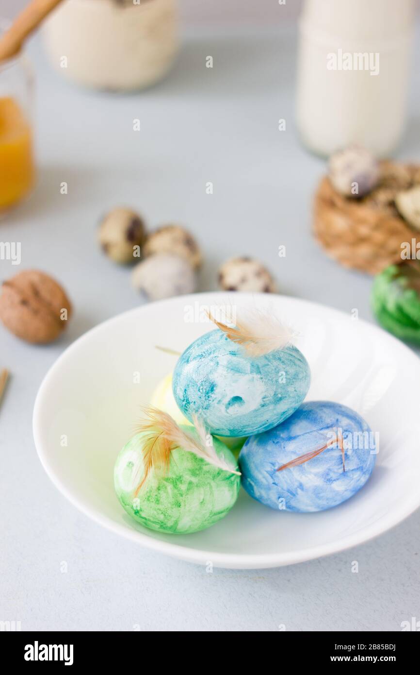 Green, yellow and blue easter eggs on ceramic bowl, bright and airy shot Stock Photo