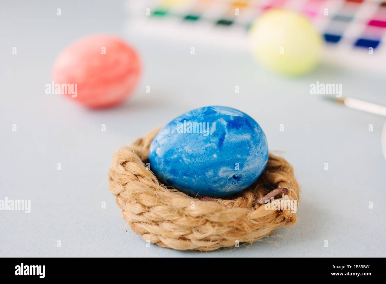 Deep blue easter egg on nest over bright background Stock Photo - Alamy