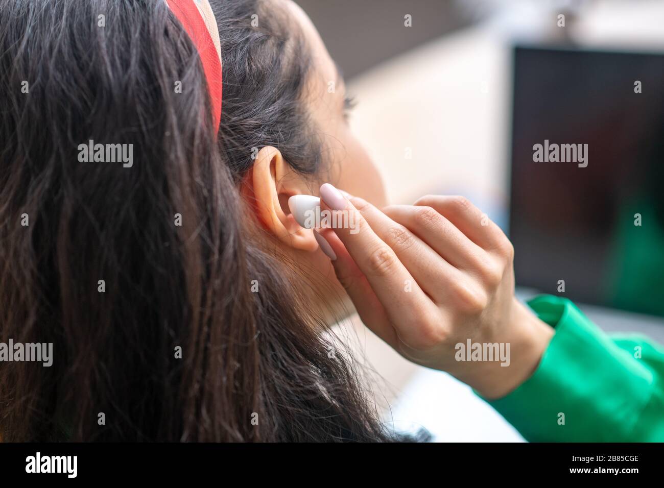 Woman with earphone near ear sitting back. Stock Photo
