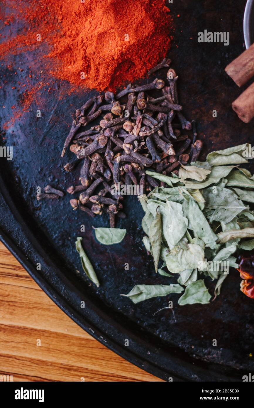 Black cloves spice over black plate surrounded by spices Stock Photo