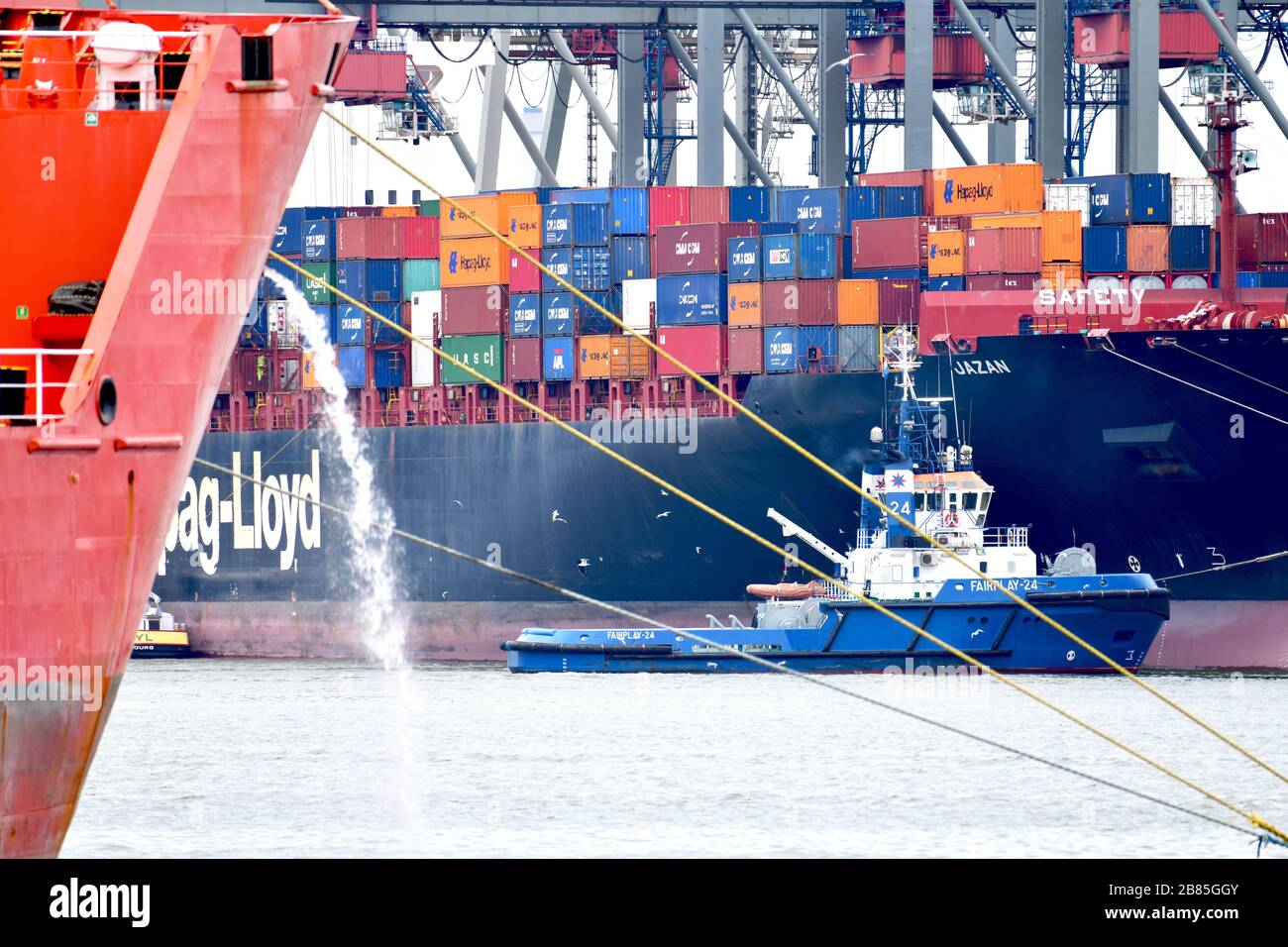 Rotterdam, The Netherlands - June 2019; compressed view of harbour activity in the container terminal, with moored ship in forefront pumping out water Stock Photo