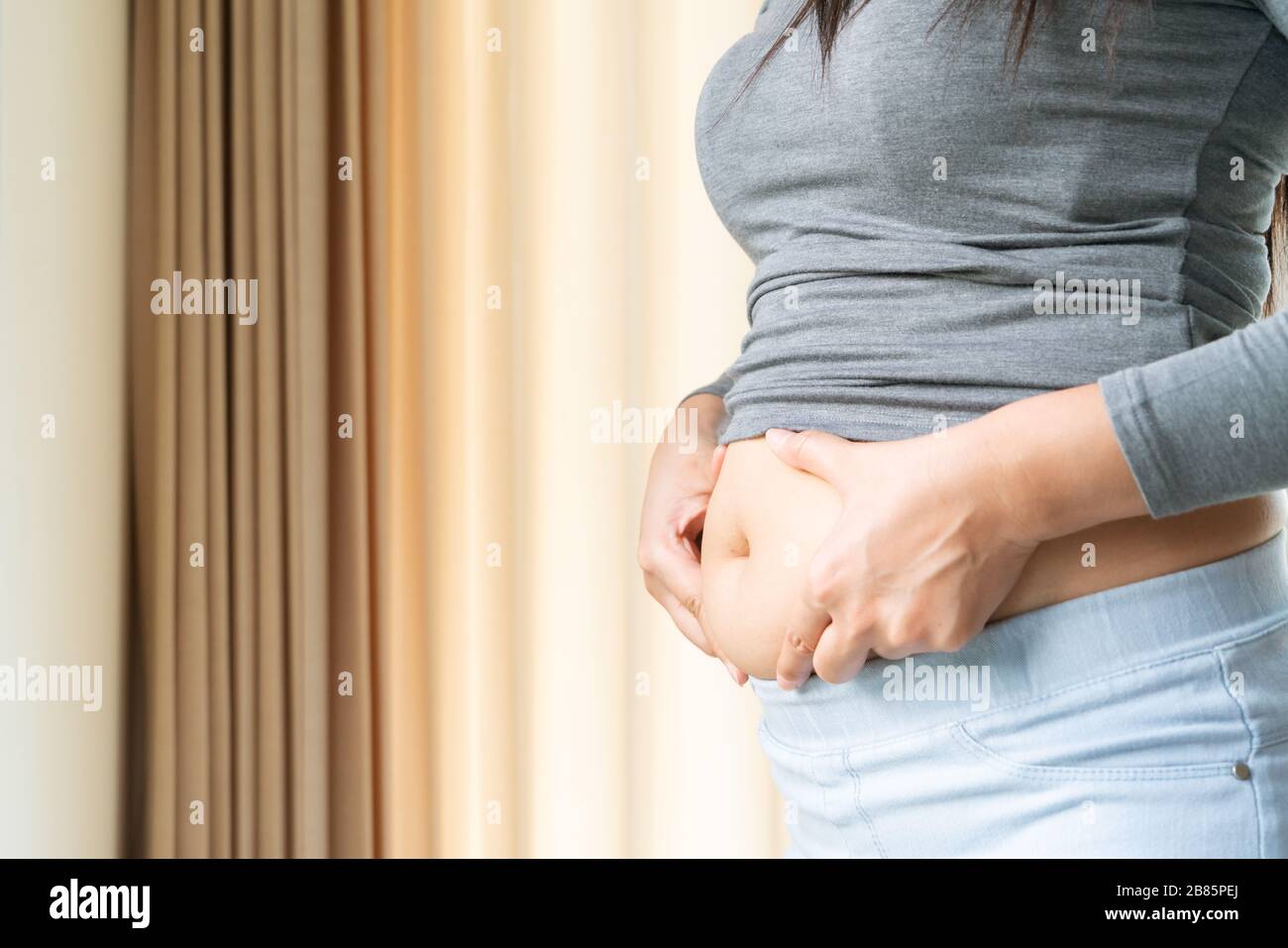 young woman's belly, women touch her fat belly, woman diet lifestyle concept Stock Photo