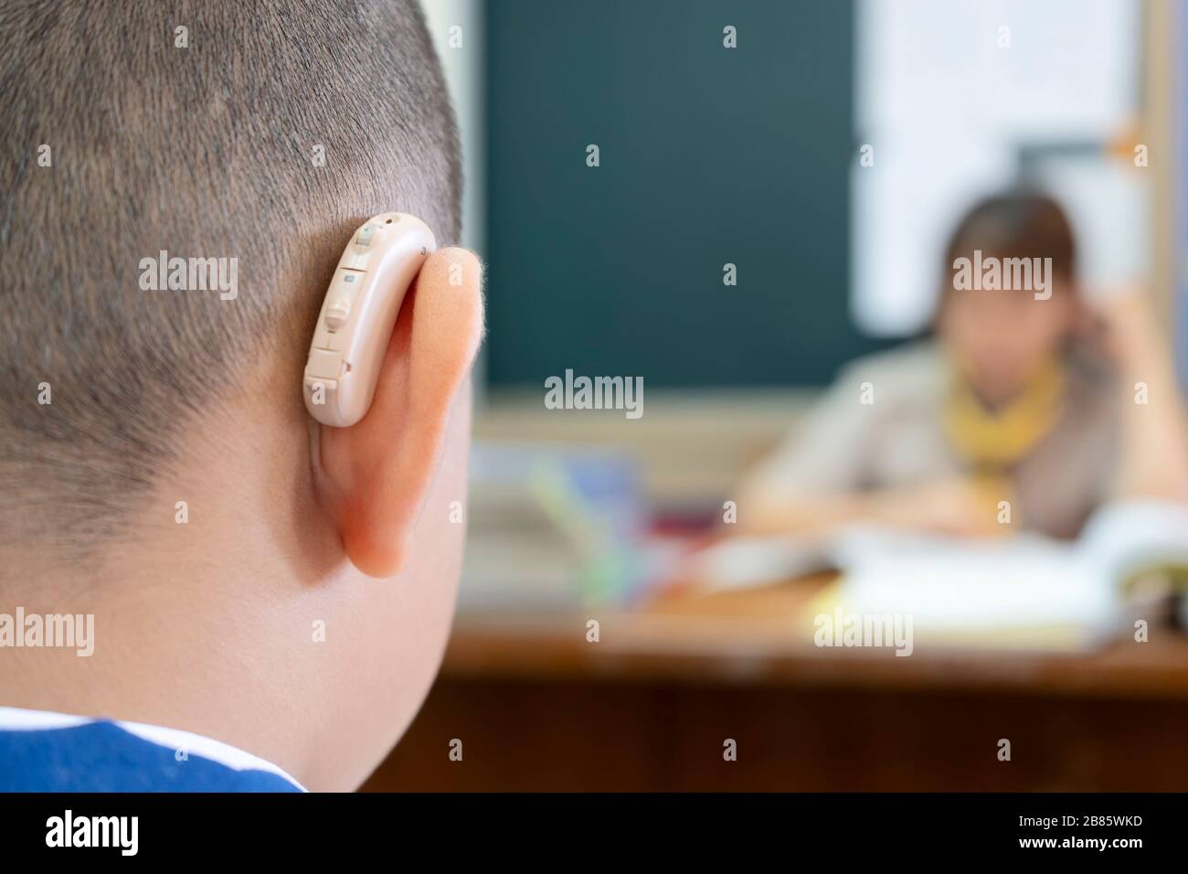 Students who wear hearing aids to increase hearing efficiency. Helps to be able to learn as much as a friend. The background is a teacher who is talki Stock Photo