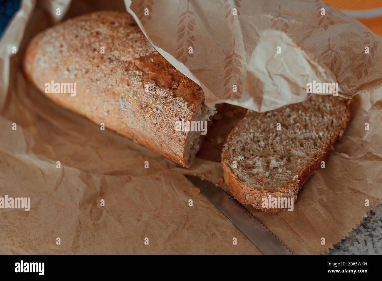 Small loaf of whole grain bread with one piece cut off with a knife Stock Photo