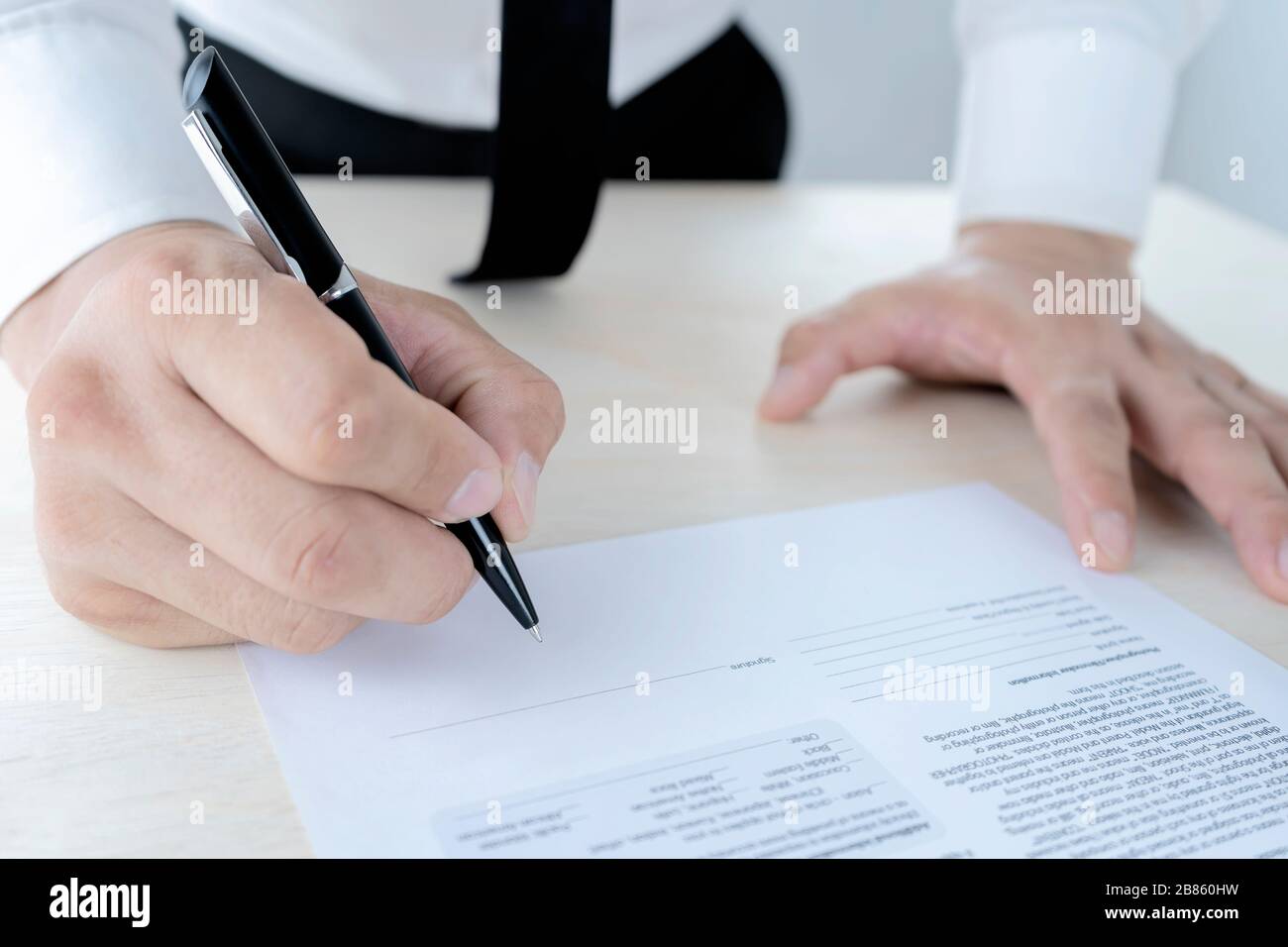 Businessmen are signing contracts. Wearing a white shirt Black slacks, black tie, dignified look