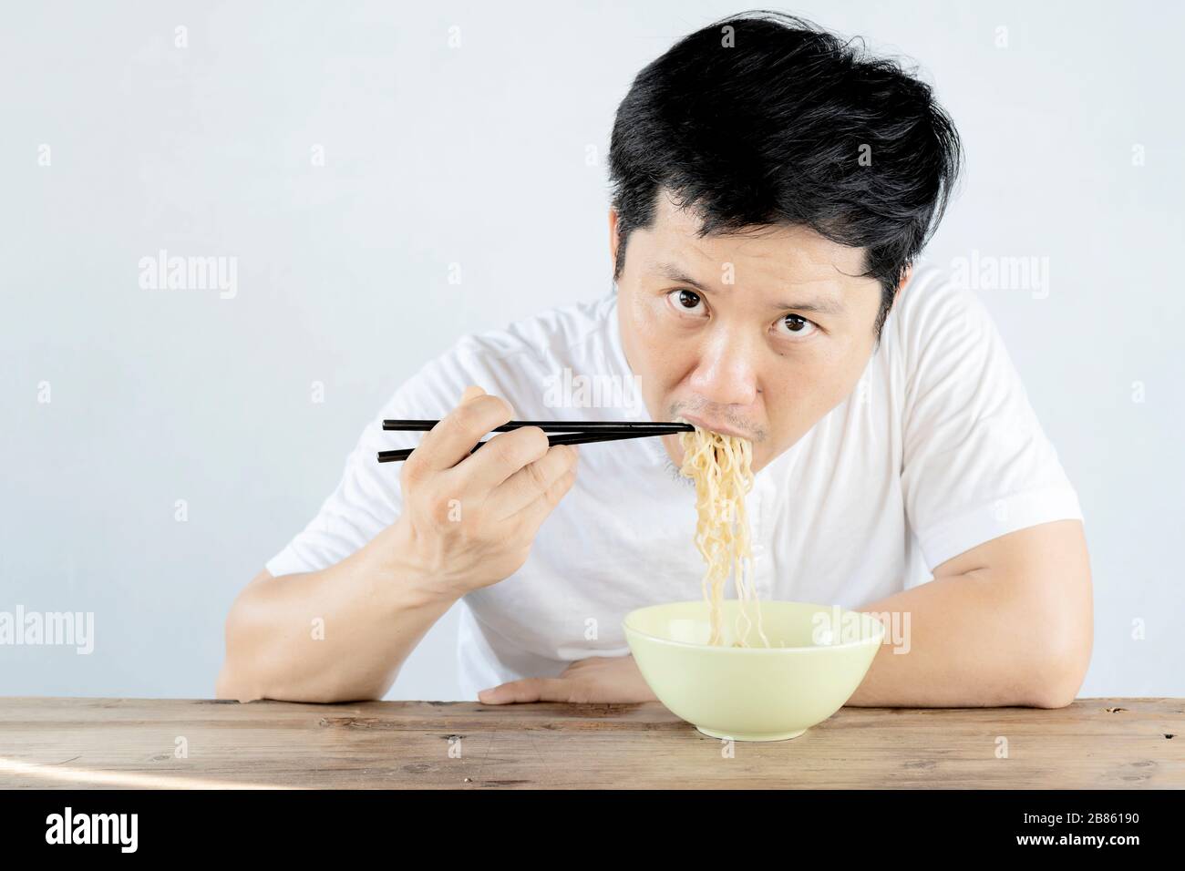 Asian men are eating instant noodles with deliciousness. Is a popular food Both delicious and cheap But lack of nutrients the body needs. Stock Photo