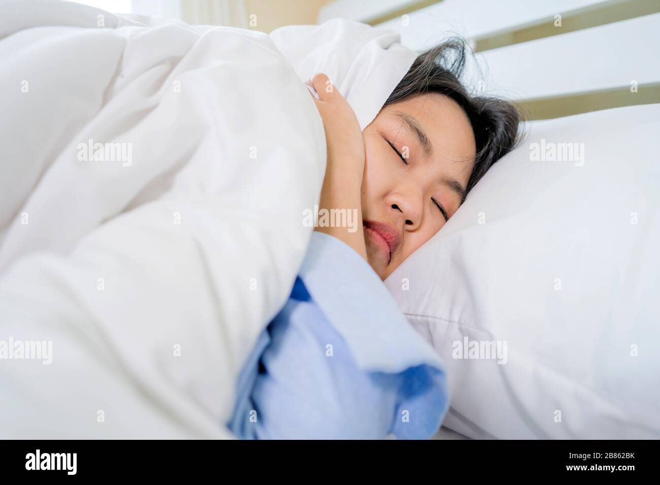 Asian women sleep very sluggishly, not waking up. In the morning, she still didn't wake up to activities. Do not want to go to work, do not want to go Stock Photo