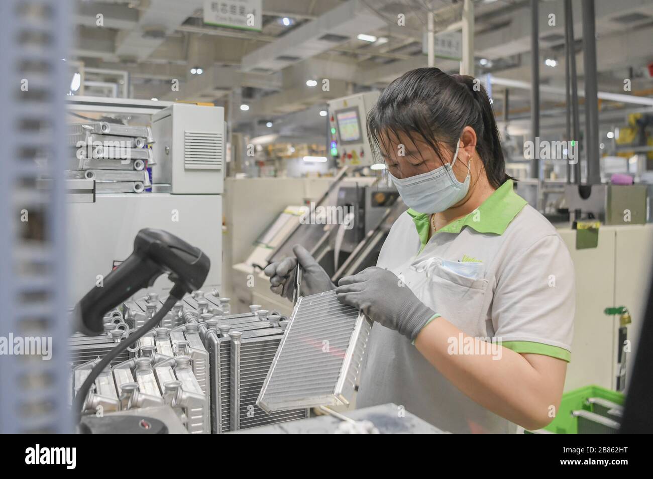 Wuhan, China's Hubei Province. 19th Mar, 2020. A staff member works on a production line at a company in Jingzhou, central China's Hubei Province, March 19, 2020. The Valeo Hubei company has resumed production since late February. Over 90% capacity of the company has recovered and over 80% staff members have returned to their work. Credit: Cheng Min/Xinhua/Alamy Live News Stock Photo