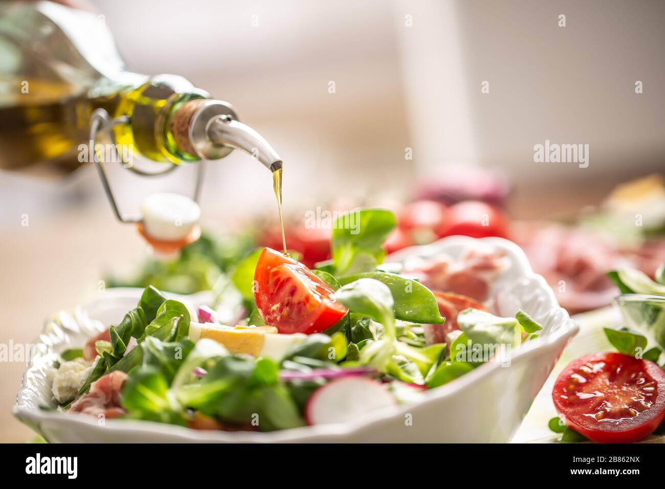 Bottle with olive oil pouring into salad Stock Photo