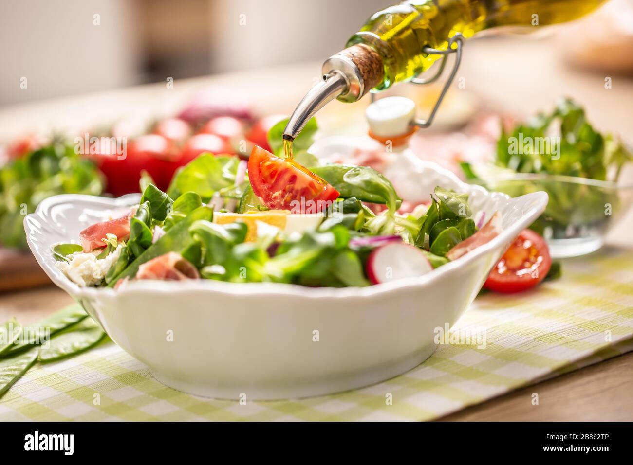 Bottle with olive oil pouring into salad Stock Photo