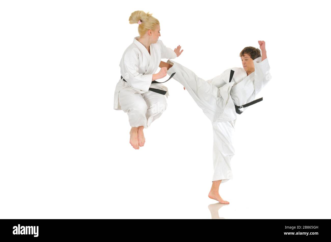 Cute blonde girl and a young cheeky guy karate are engaged in training in a kimono on a white background. Young couple of athletes getting ready for a Stock Photo