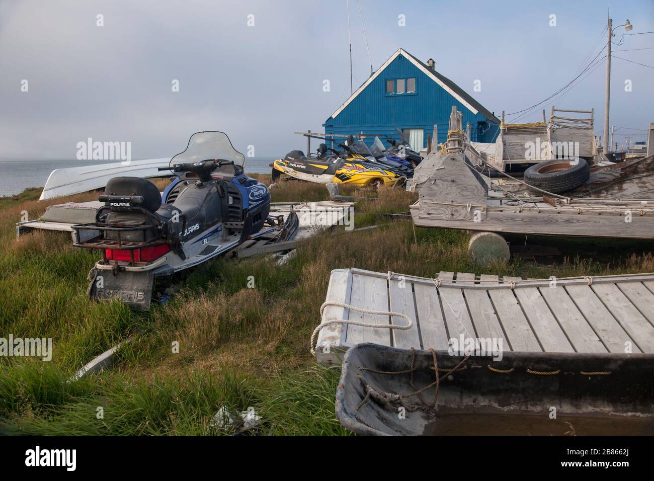 Inuit house close to the Artic Ocean seashore surrounded by jet-skies, sleighs and a boat, Barrow, Alaska Stock Photo