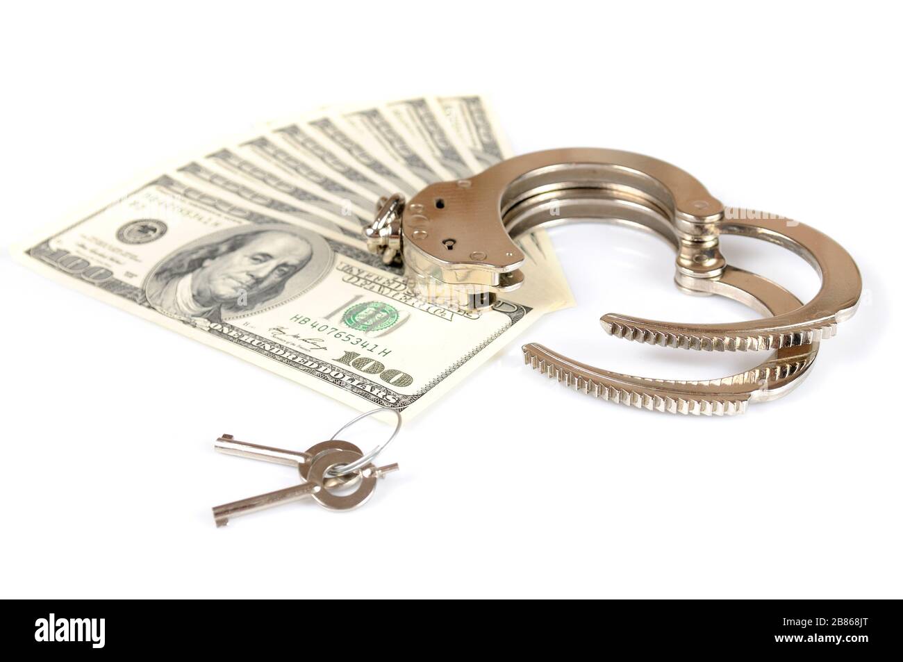 Closeup of open metal handcuffs, keys and stack of american dollars