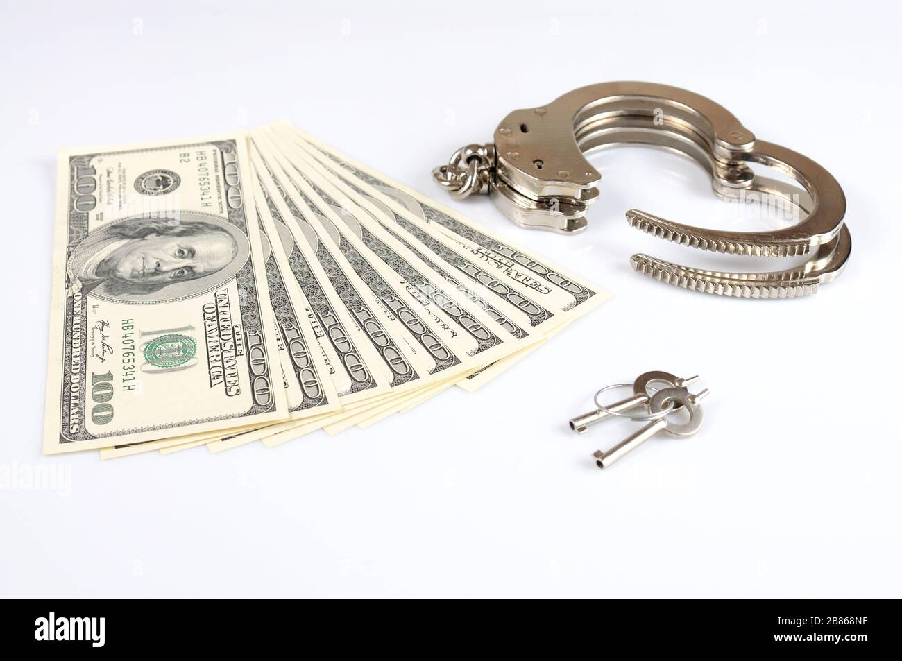 Closeup of open metal handcuffs, keys and stack of american dollars