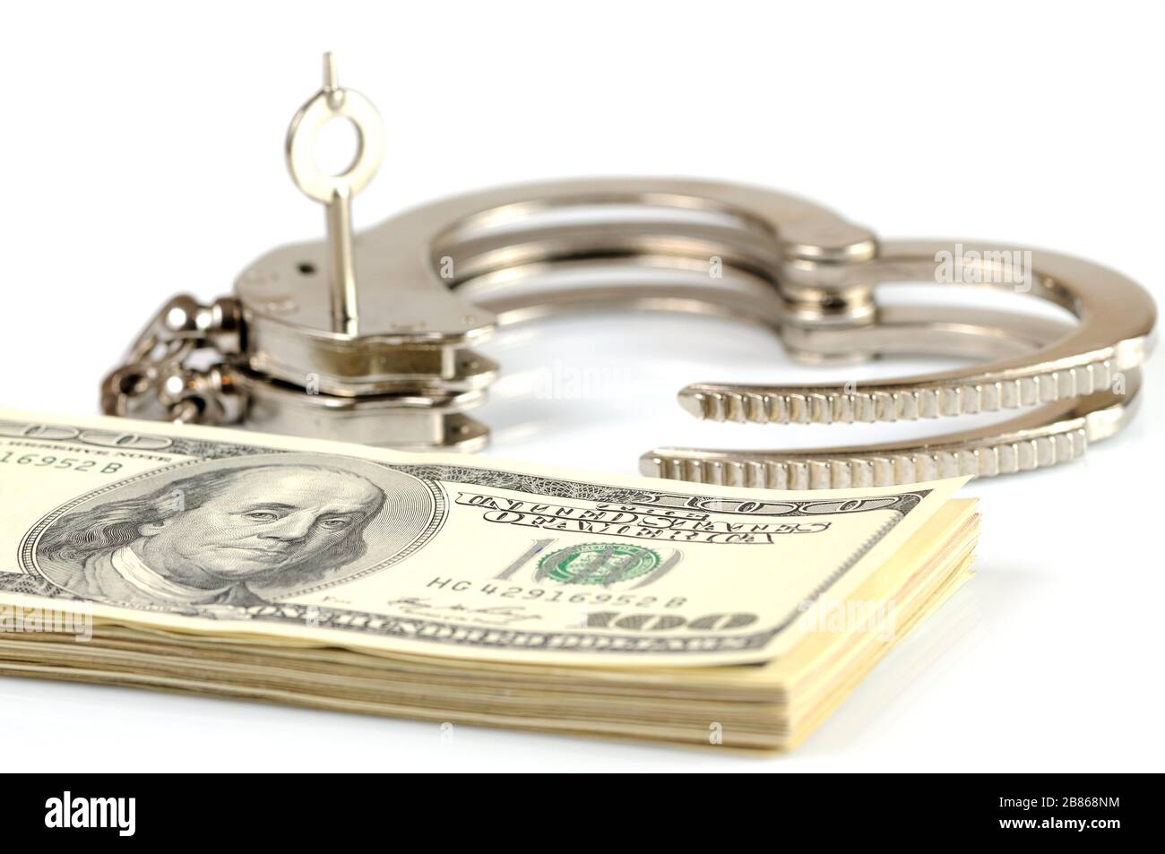 Closeup of open metal handcuffs, keys and stack of american dollars