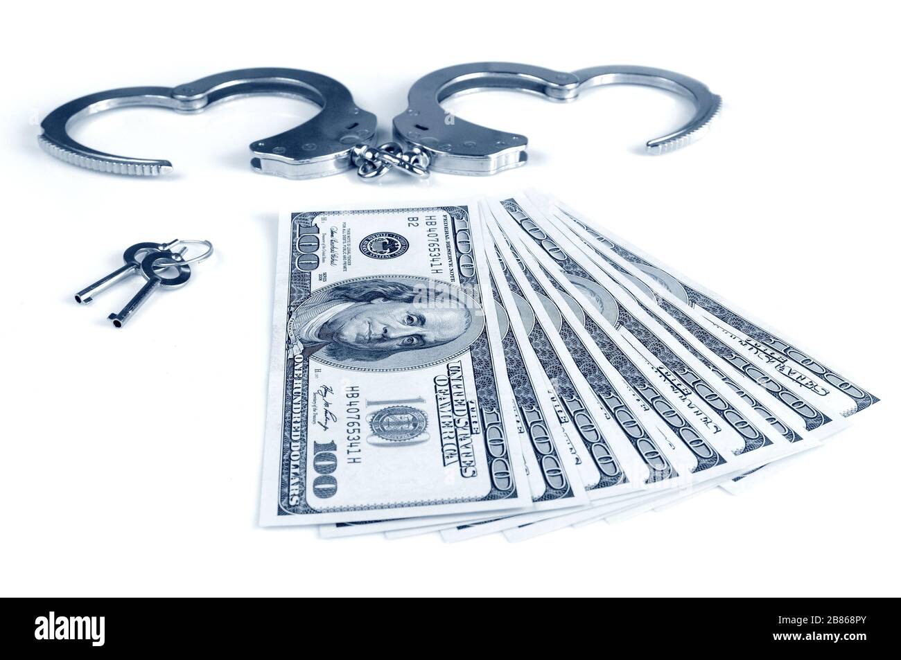 Closeup of open metal handcuffs, keys and stack of american dollars