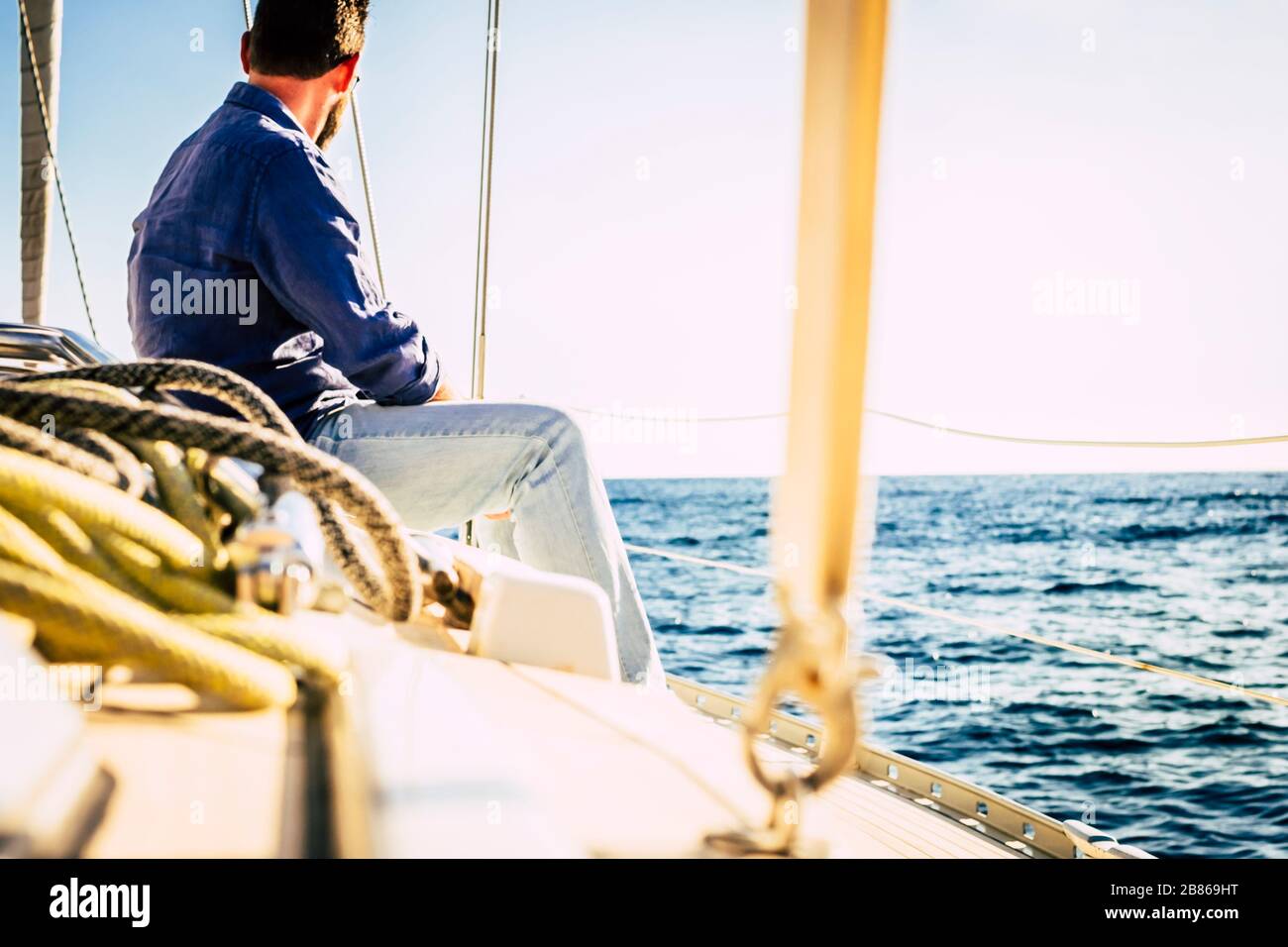Man sit on a sail boat travel the ocean and enjoy freedom lifestyle - concept of sailing and having fun during summer holiday vacation in alternative Stock Photo
