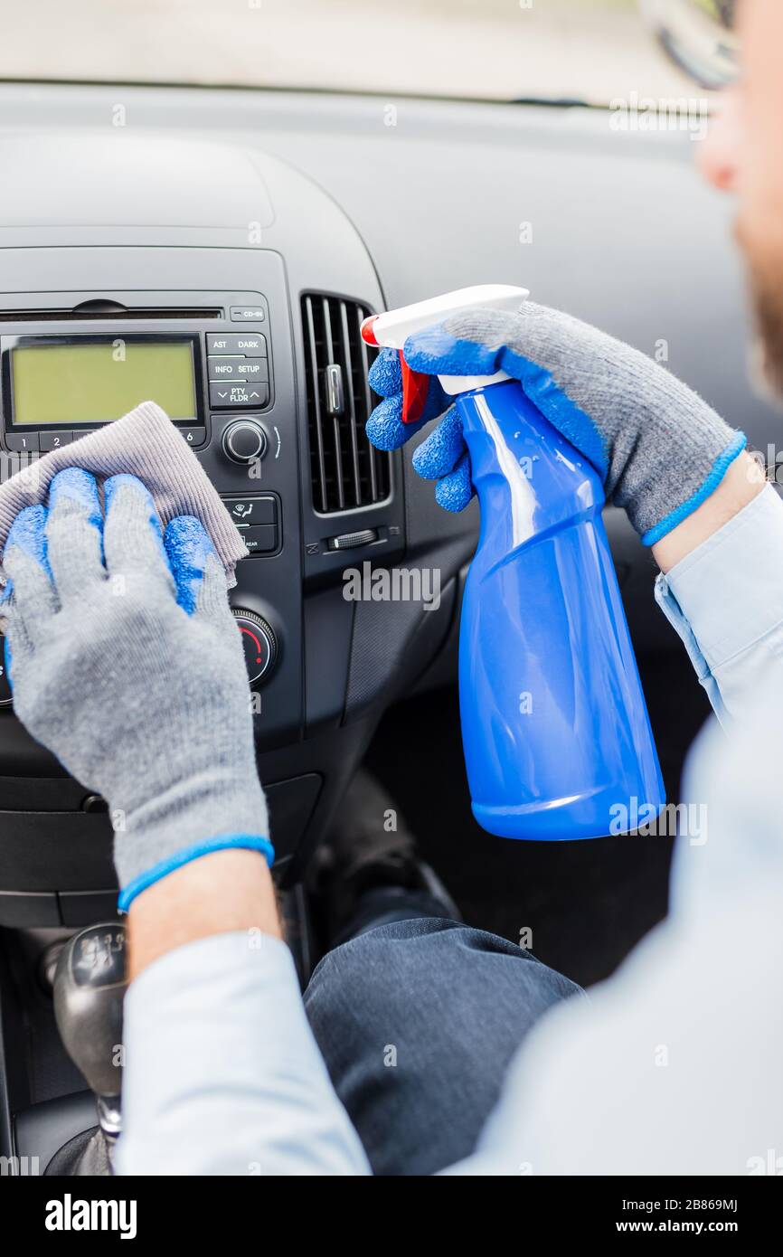 Cleaning car dashboard concept. Car wash worker using disinfectant and