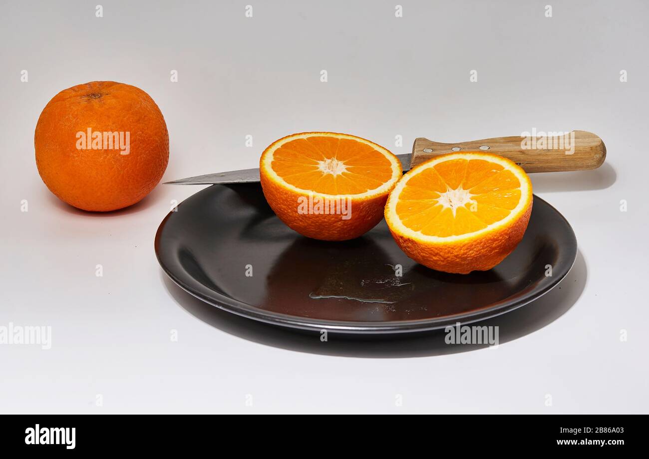 still life of a cut orange on a black plate with white background Stock Photo