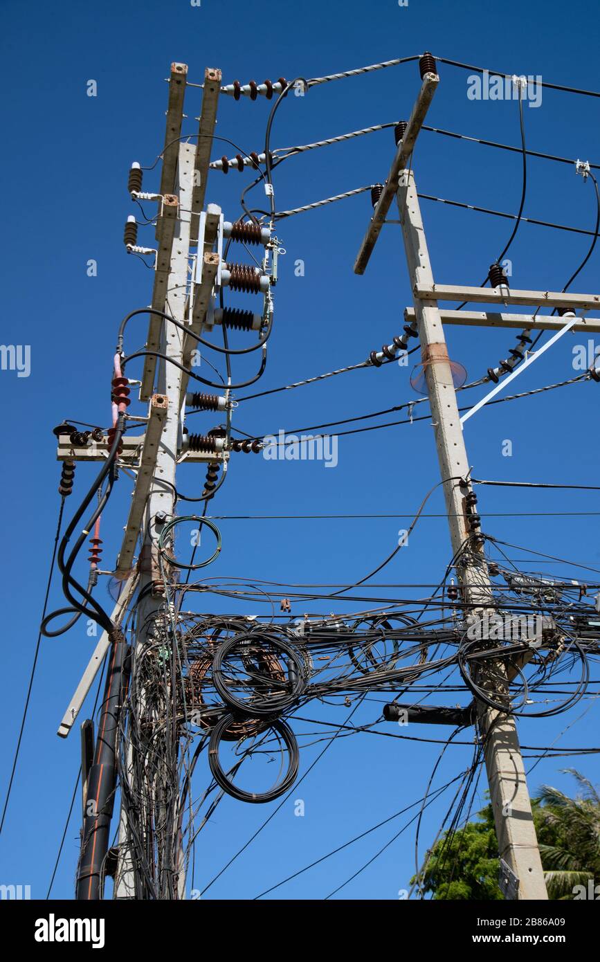 Electric wires and cables installed on the pole Looking confused in Bangkok, Thailand with a blue sky as a background. Stock Photo