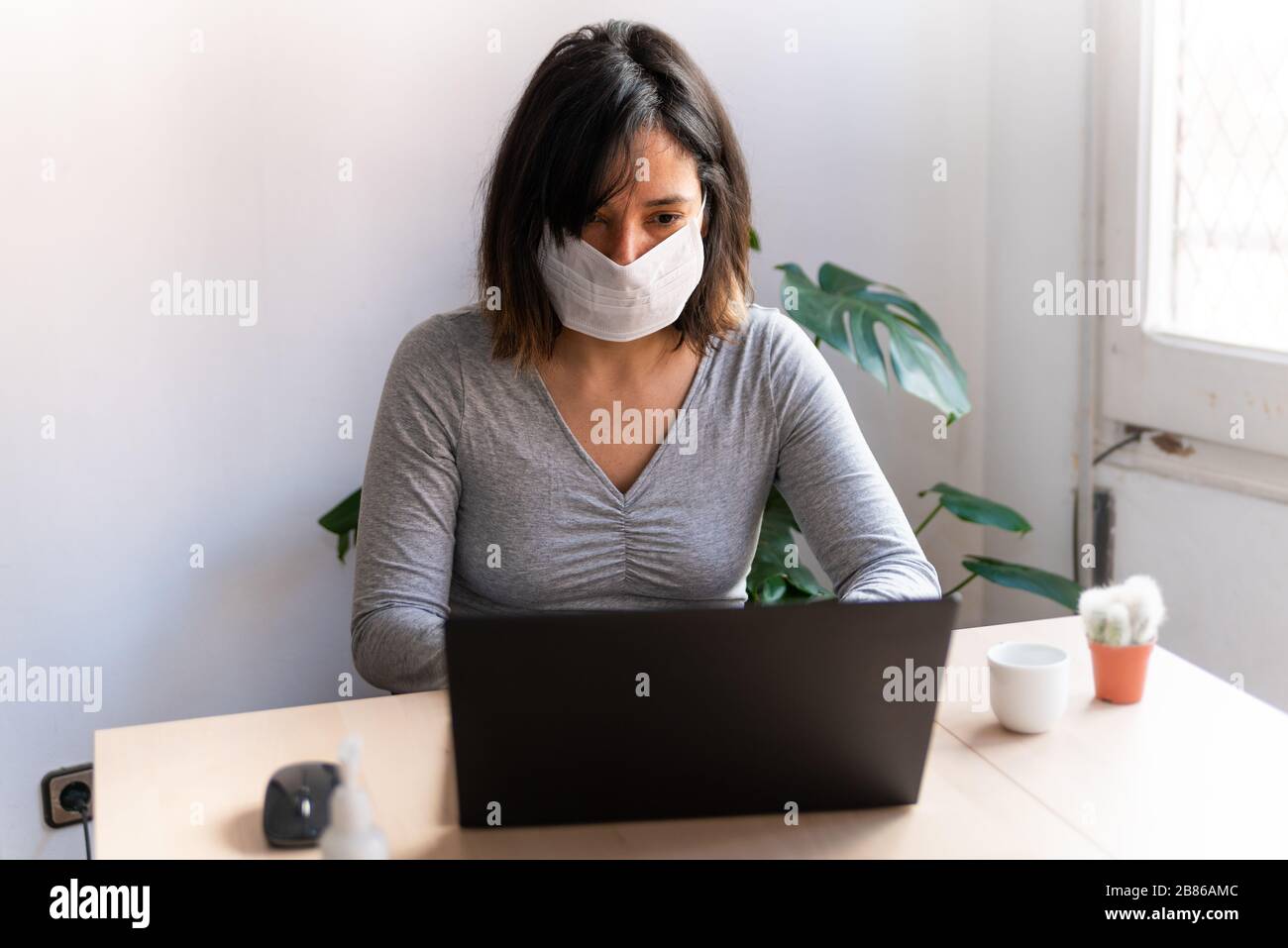 young woman wearing protective face mask and with hand sanitizer work from home office due to corona virus outbreak, quarantine is a measure take to s Stock Photo