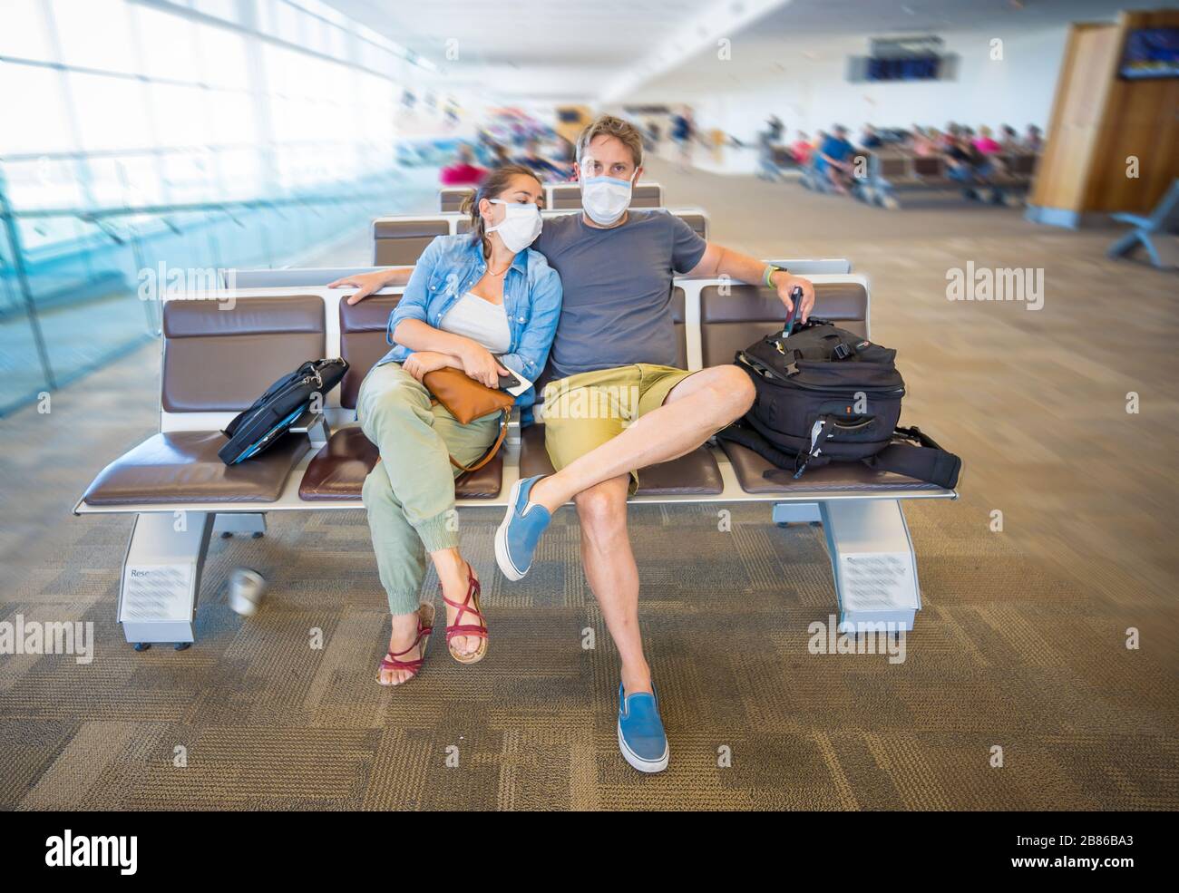 Coronavirus outbreak travel restrictions. Travelers with face mask at international airport affected by flights cancellations and travel ban. COVID-19 Stock Photo
