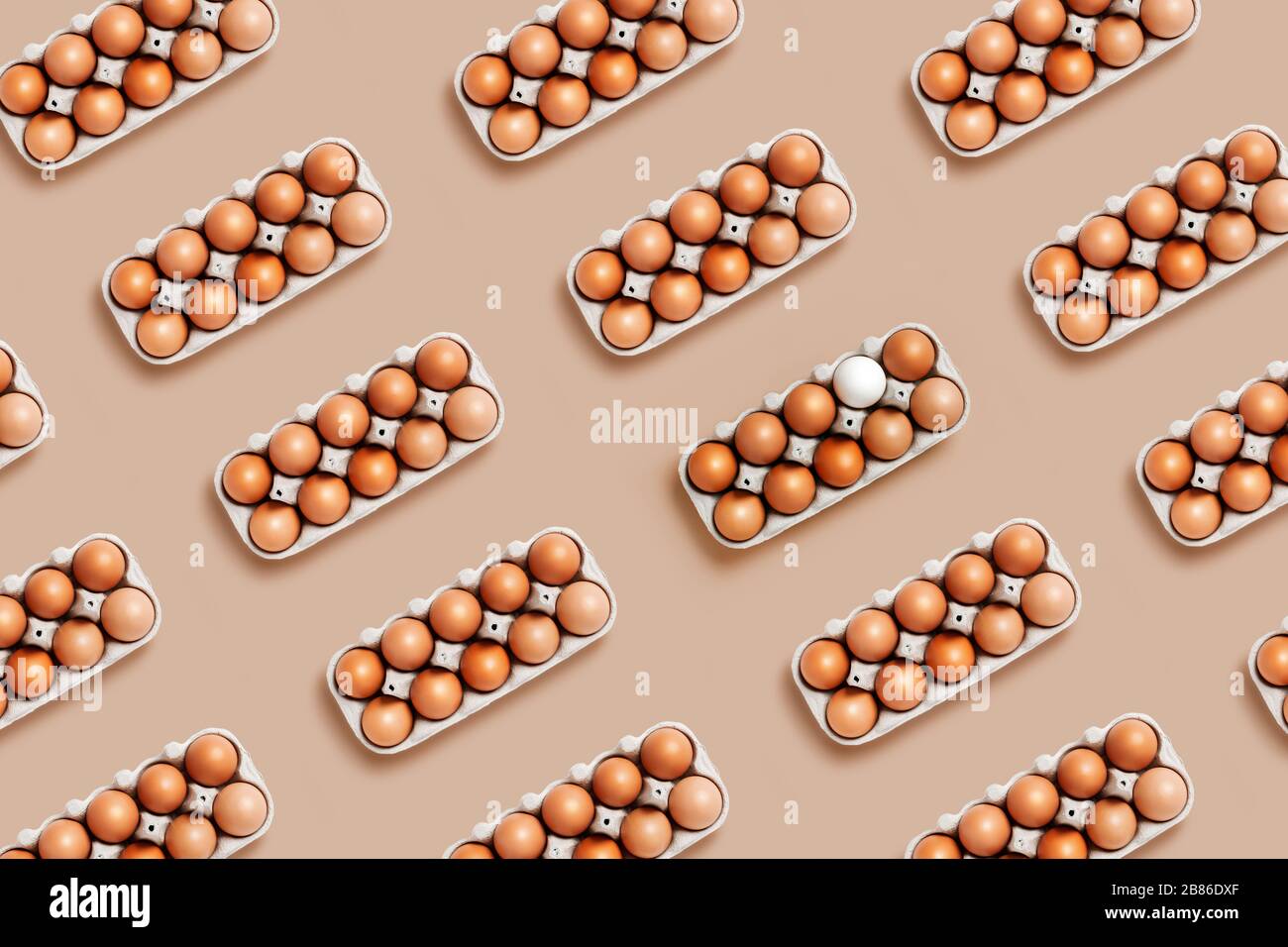 A dozen eggs in a box on the table with one white eggin the pattern. Minimalistic product concept Stock Photo