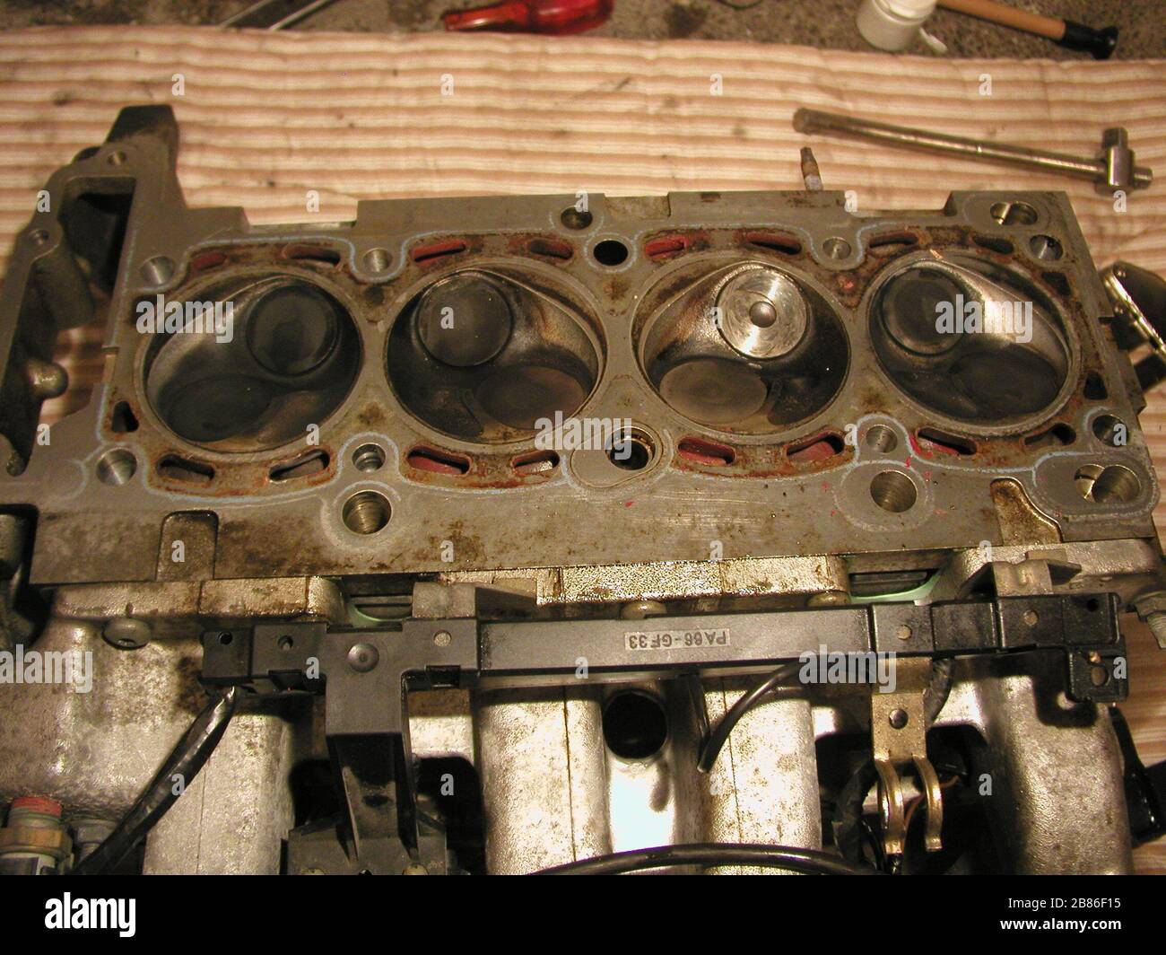 'The cylinder head of the en:Ford I4 DOHC engine, seen from its bottom side. The intake manifold has been left on and is visible on the bottom side of the image, while the exhaust manifold has been removed to replace an exhaust valve, as seen by the much shinier valve in the second combustion chamber from the right.; 18 September 2006 (original upload date); Transferred from en.wikipedia to Commons.; Dolda2000 at English Wikipedia; ' Stock Photo